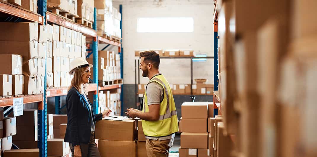 worker discusses industrial real estate market dynamics with facility manager in distribution warehouse